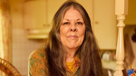 Profile shot of Loreen Willenberg, a woman with long hair and smiling at the camera, at home in her kitchen